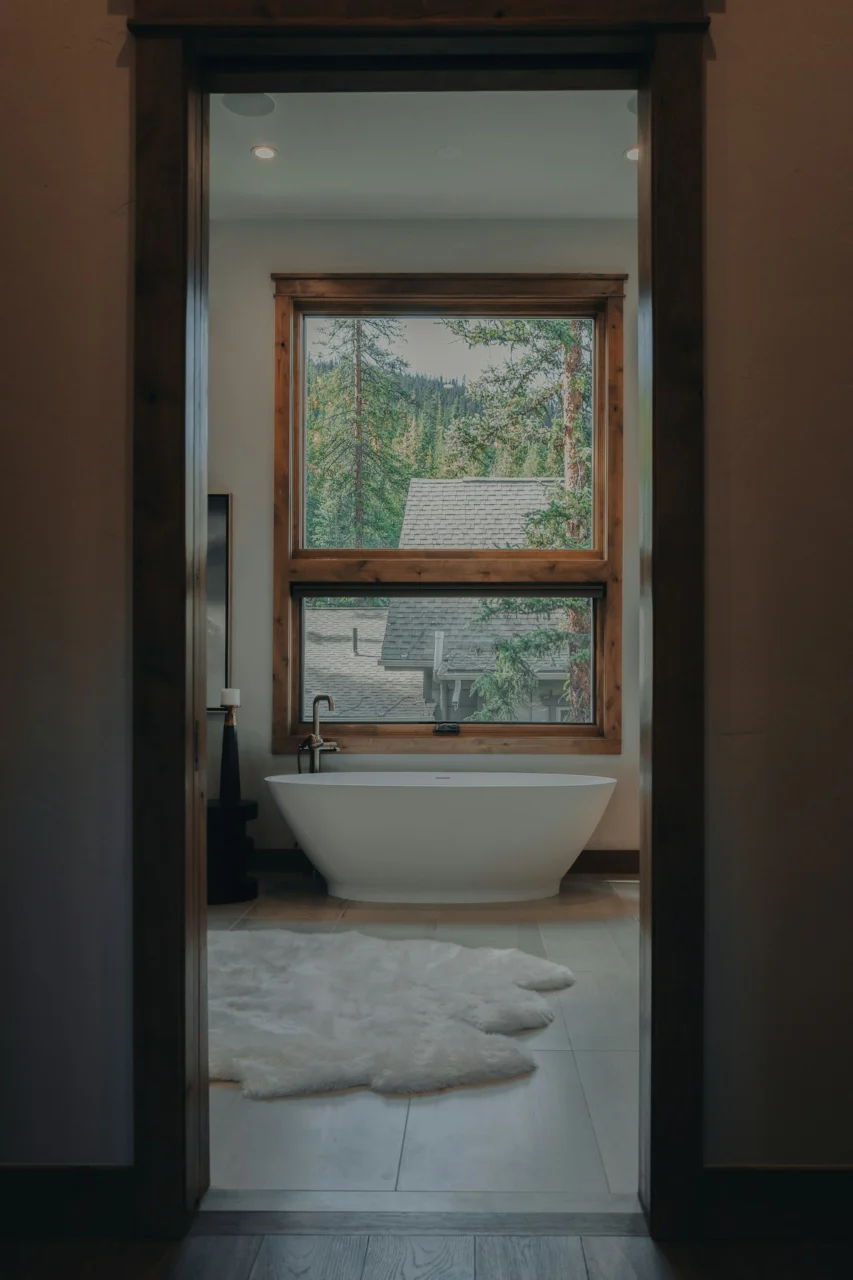 A bath room with a tub a window and a rug