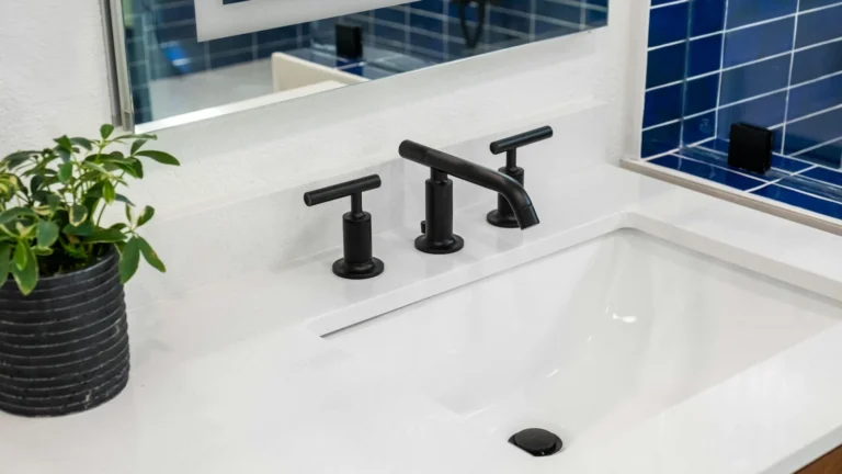 a bathroom sink with a black faucet and a blue tiled wall