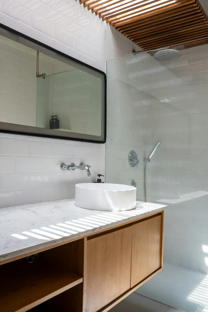 A bathroom with a sink, mirror, and shower