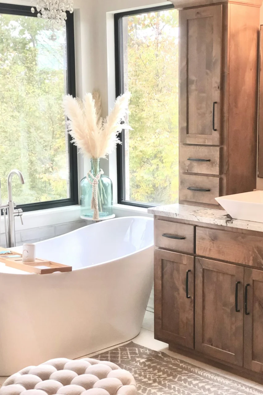 a bathroom with a tub, sink, cabinets and a window