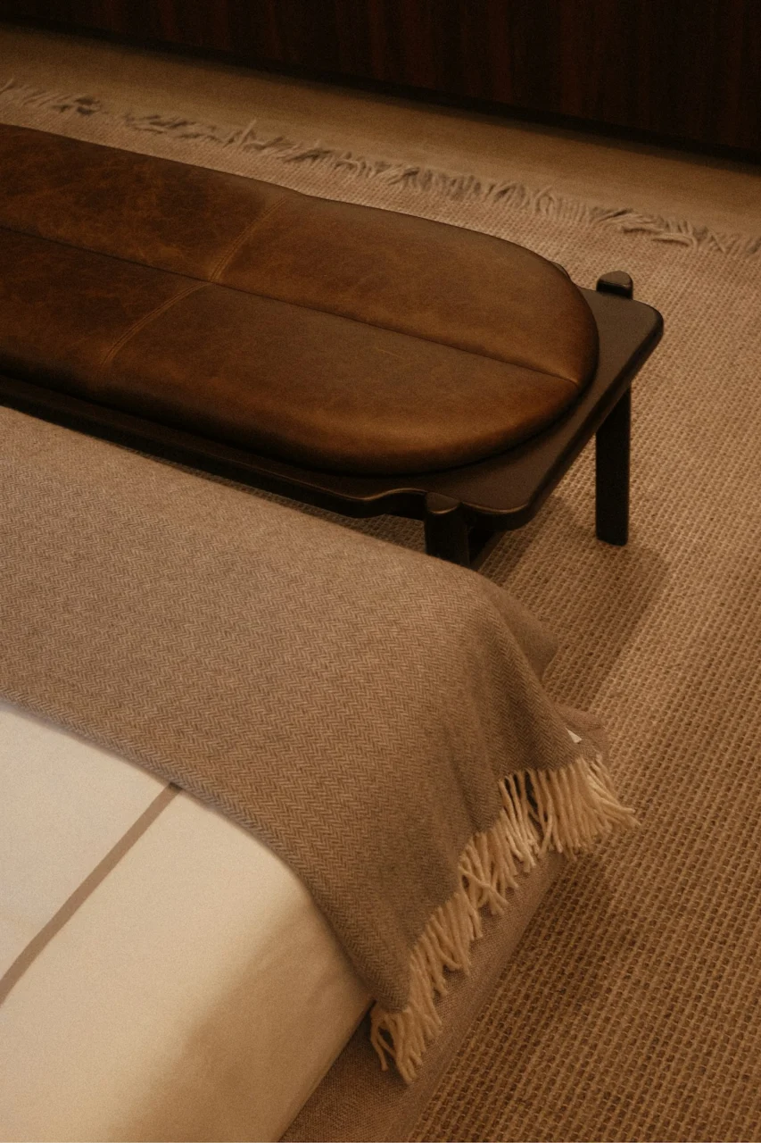 A bed with a bench and a soft blanket