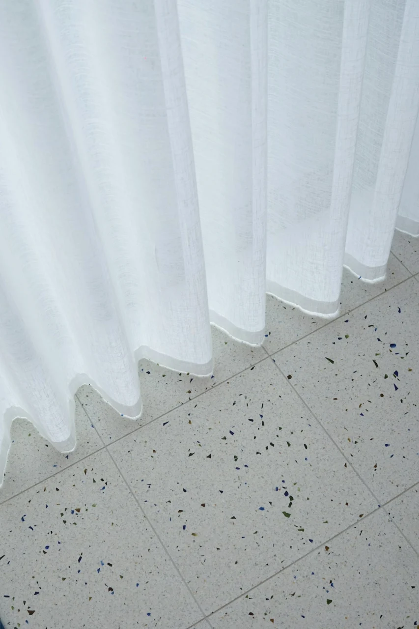 a cat sitting on the floor next to a curtain