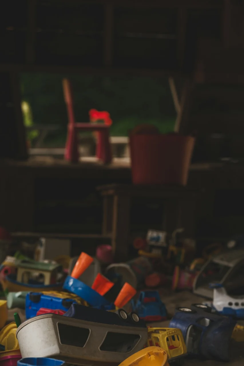 A collection of colorful plastic toy vehicles scattered on a dark floor