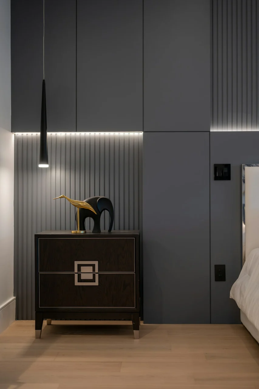 A dark wooden nightstand with a gold bird and black elephant figurine
