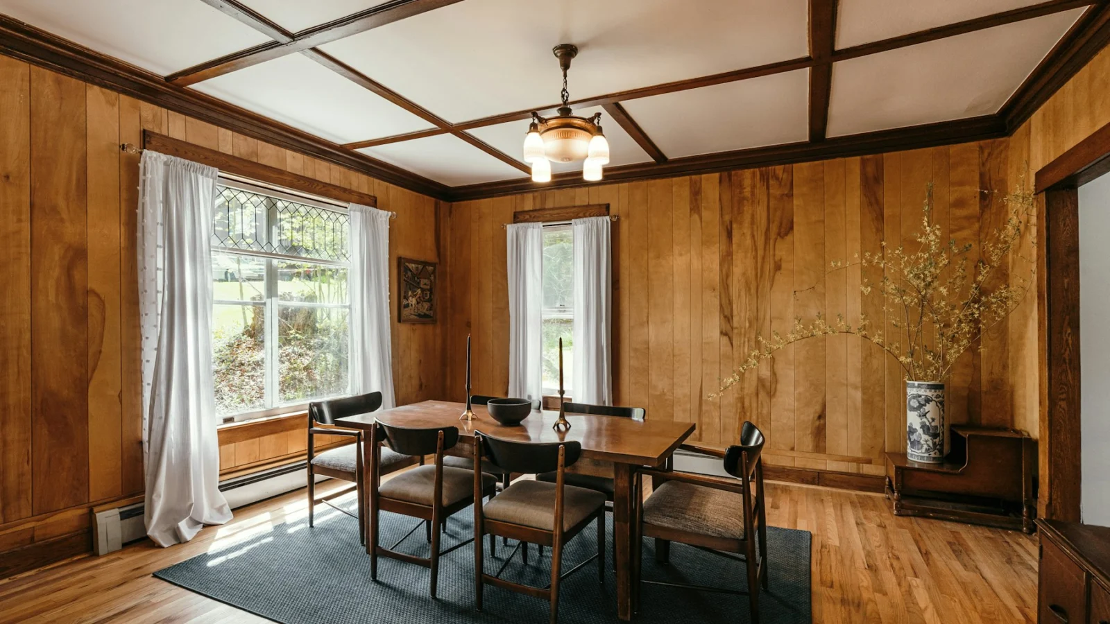 a dining room with wood paneling and windows