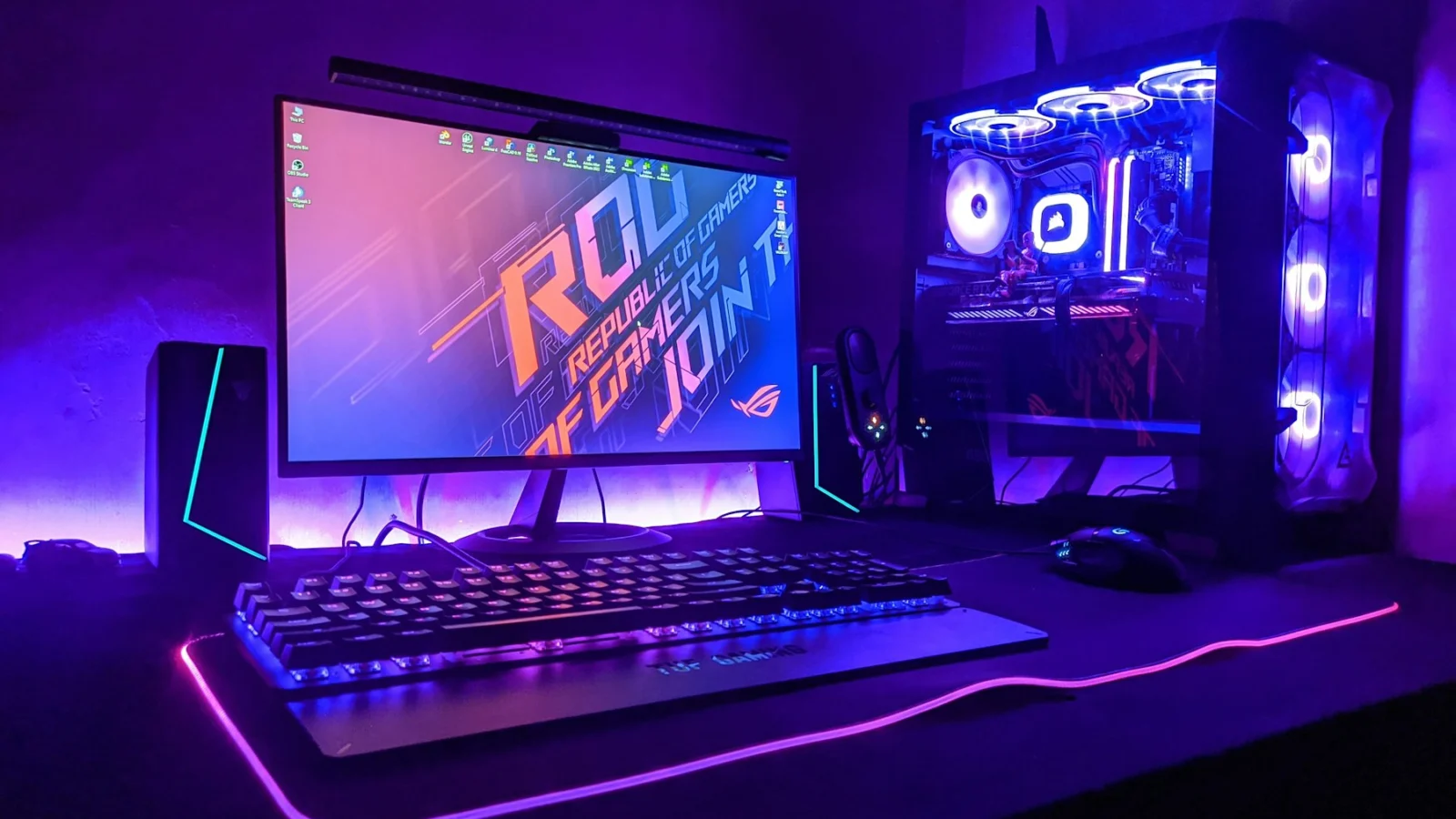 A gaming computer setup with a monitor, keyboard, and tower in purple light