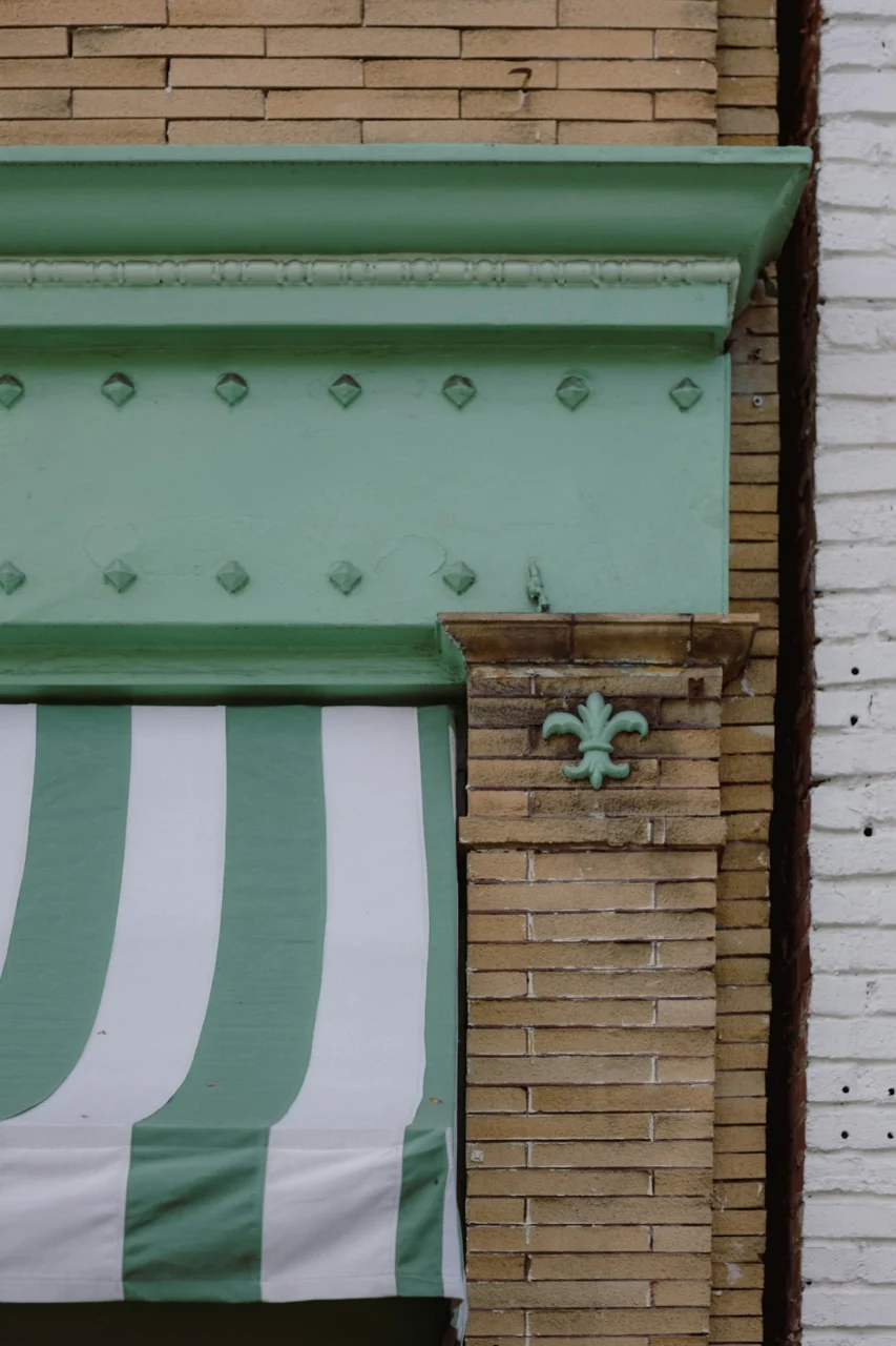 a green and white striped awning next to a brick building
