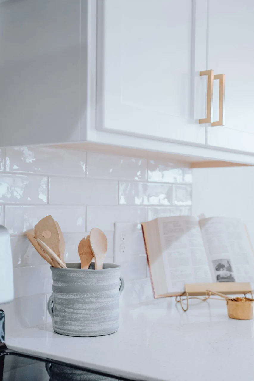 A kitchen counter with a book and wooden utensils