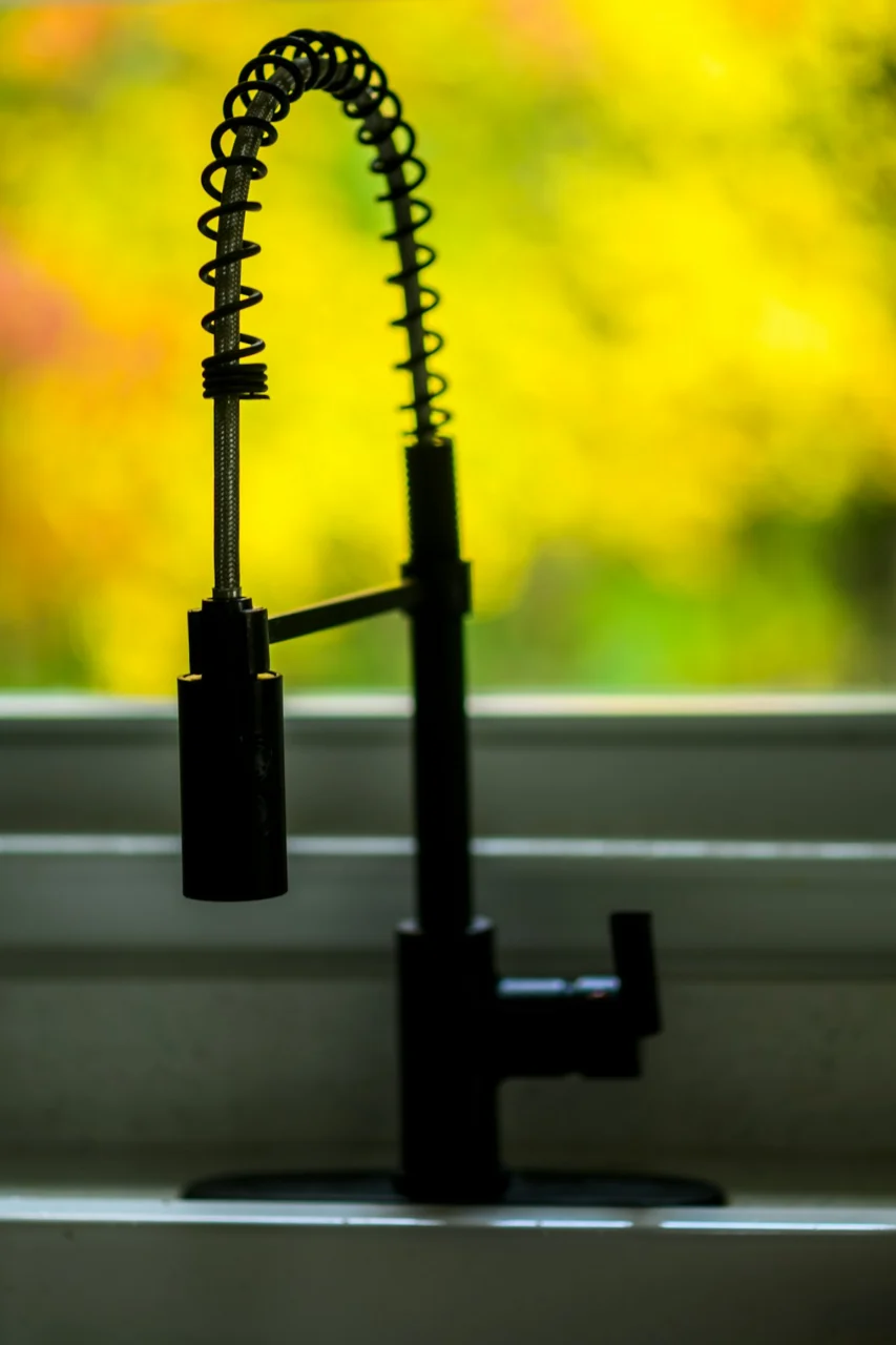 a kitchen sink with a faucet and a window in the background