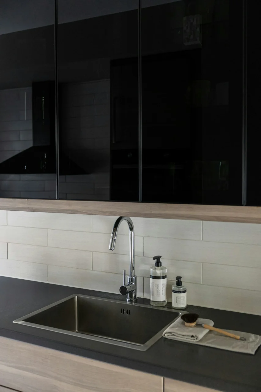 A kitchen with black cabinets and a black sink