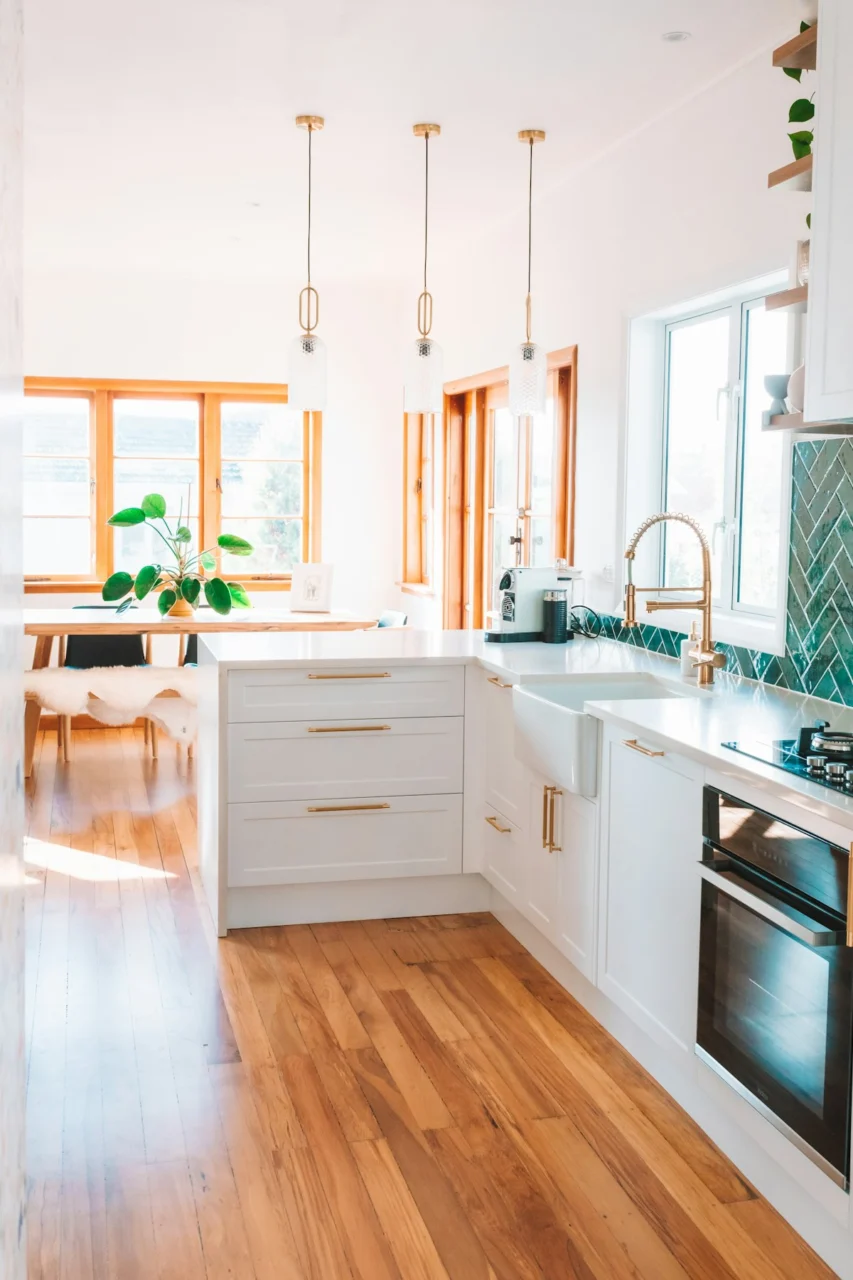 a kitchen with white cabinets and wood floors