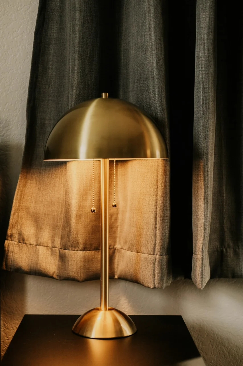 a lamp sitting on top of a table next to a window