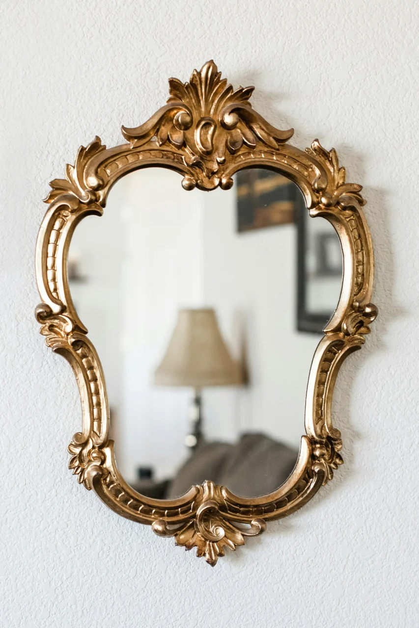 a mirror hanging on a wall next to a lamp