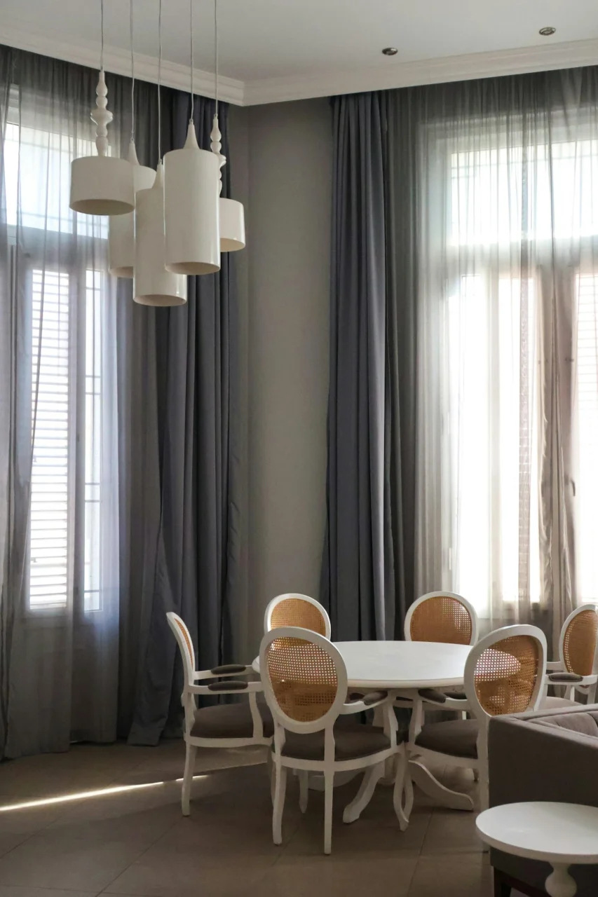A modern dining room with chandelier and gray curtains