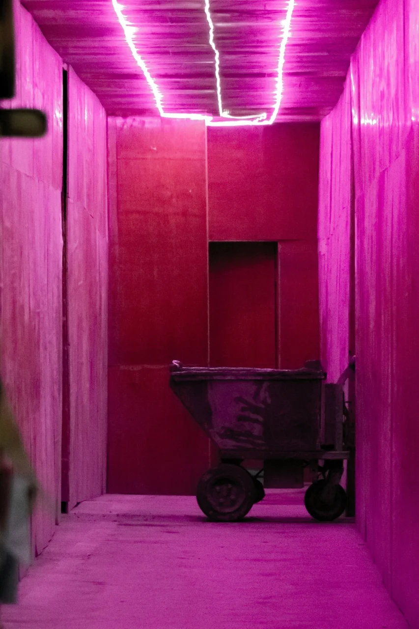 A pink-lit corridor with a cart at the end