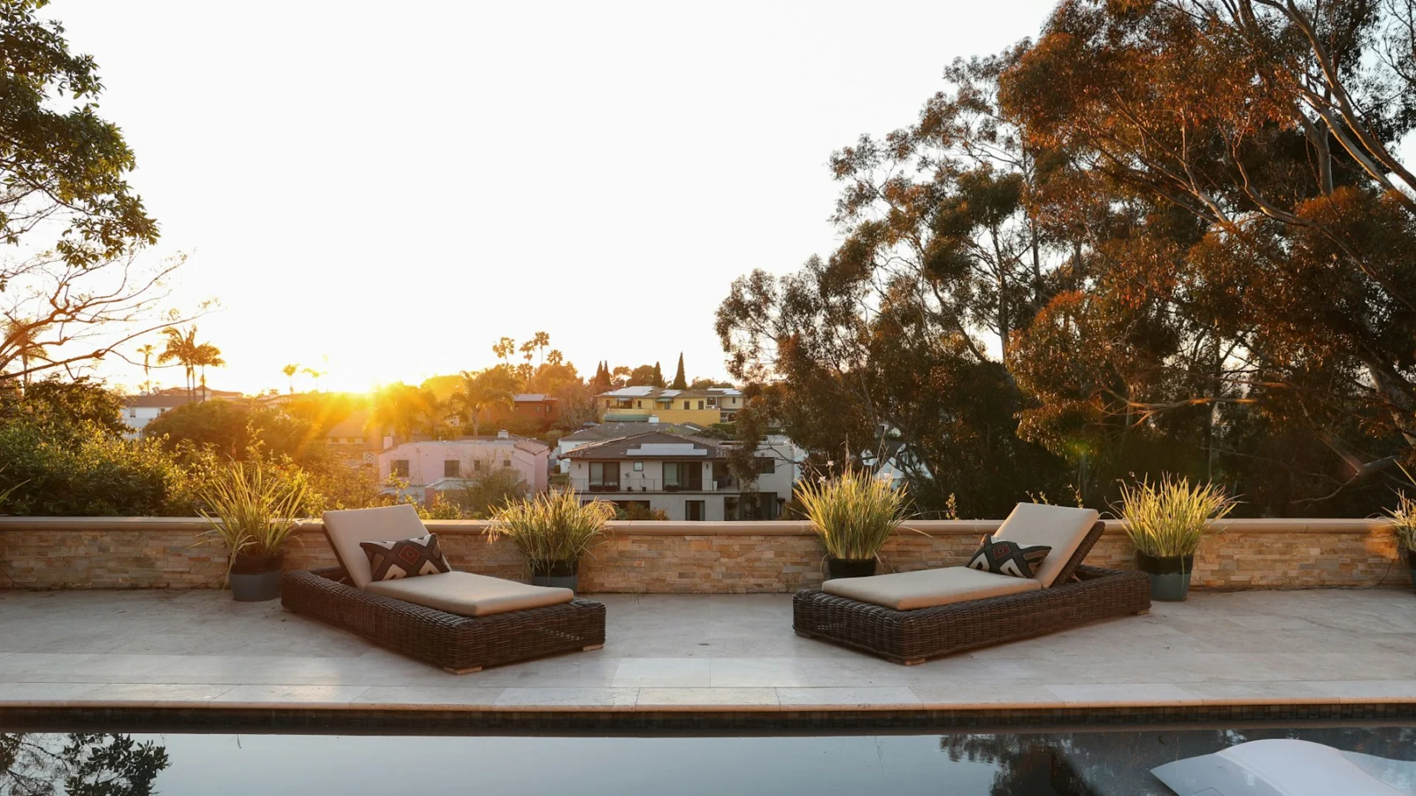 a pool with two lounge chairs and a view of a house