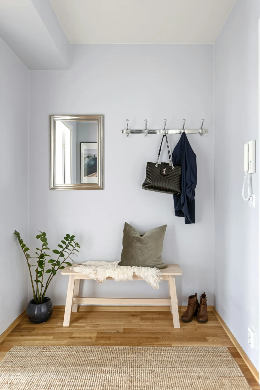 A room with a bench, mirror, coat rack and plants