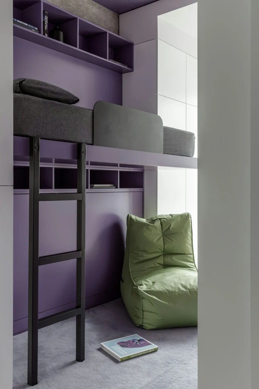 A room with a bunk bed and a green chair