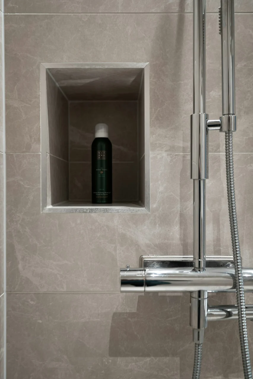 A shower head with a bottle of deodorant next to it