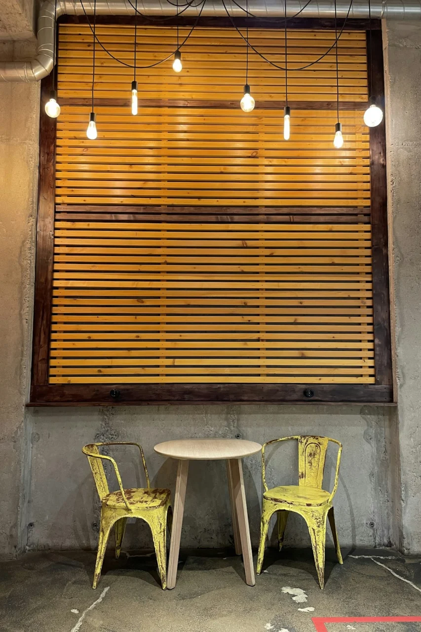 a table and chairs in front of a wood wall with lights