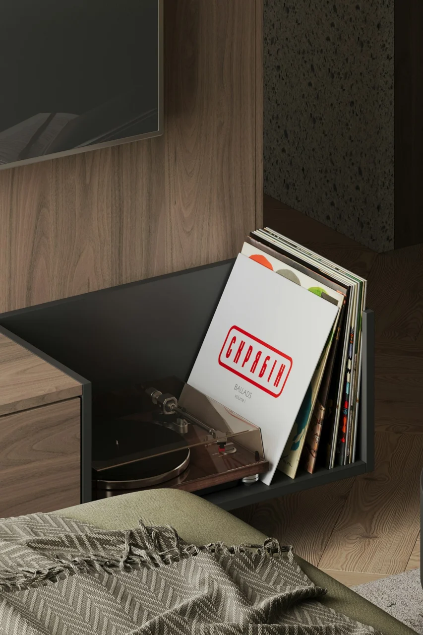 A television sitting on top of a wooden shelf next to a bed