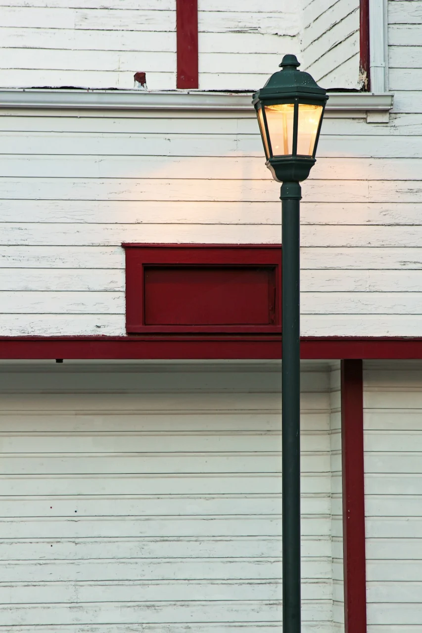A vintage lamppost stands before a weathered building