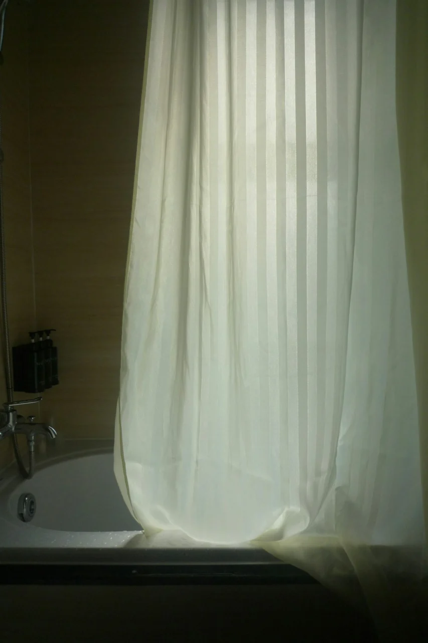 A white striped shower curtain drawn across a bathtub