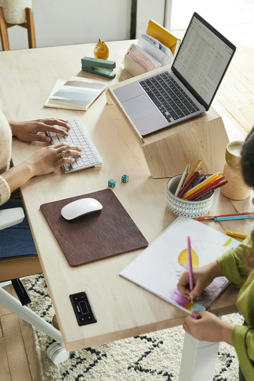 a woman sitting at a table with a child using a laptop