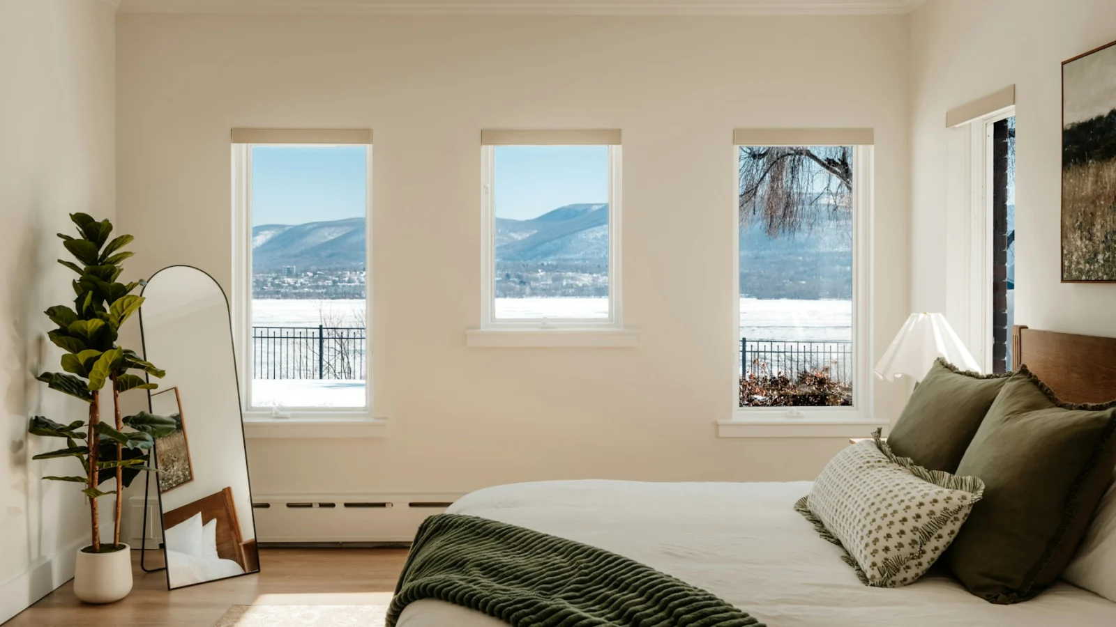 Bedroom with a view of snowy mountains through three windows