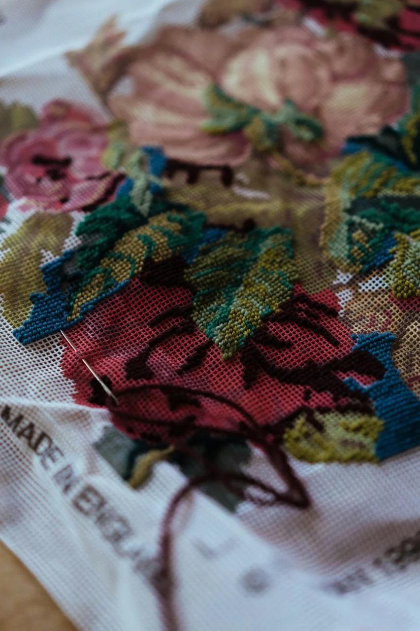 Close-up of needlepoint floral art with needle and thread