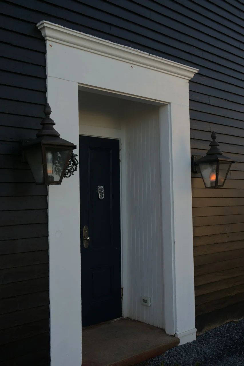 Dark exterior with white trim and two lanterns