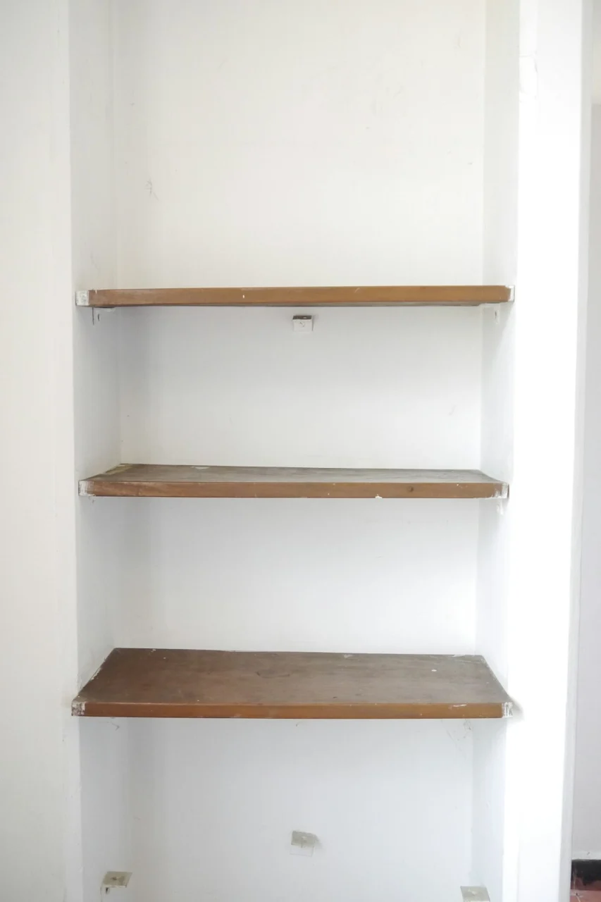 empty shelves in a white room with a tile floor