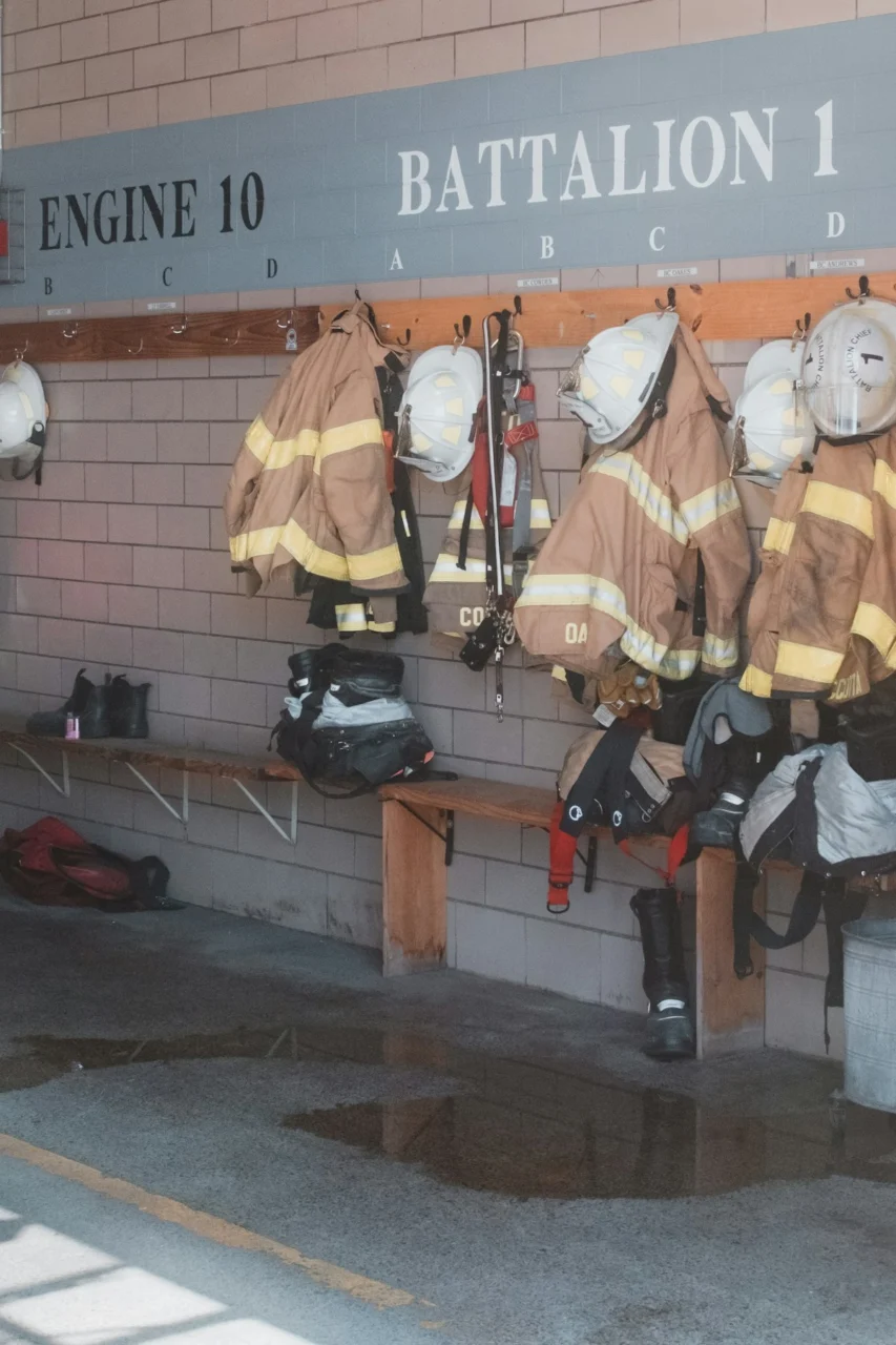Firefighter gear hangs on hooks in a station