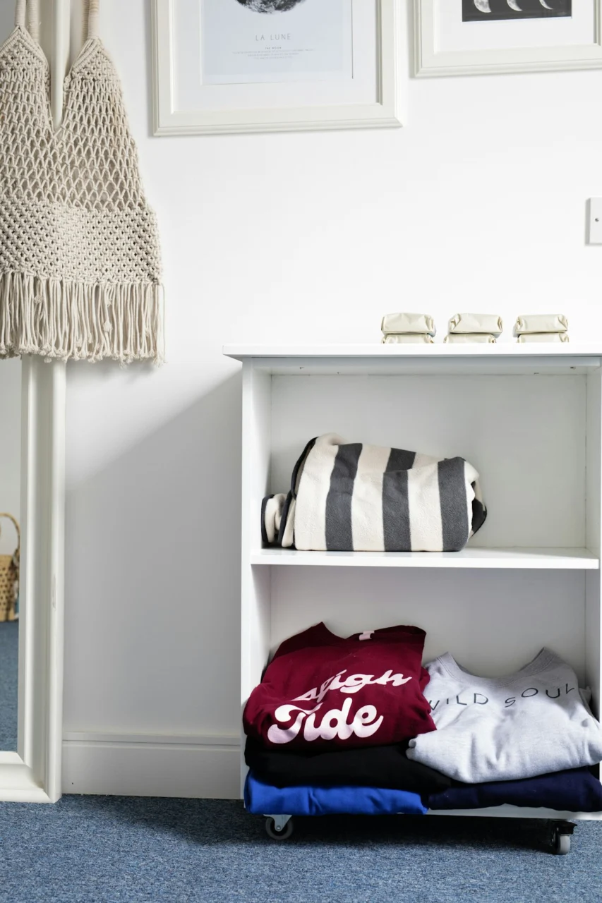 Folded clothes and striped bag on shelf