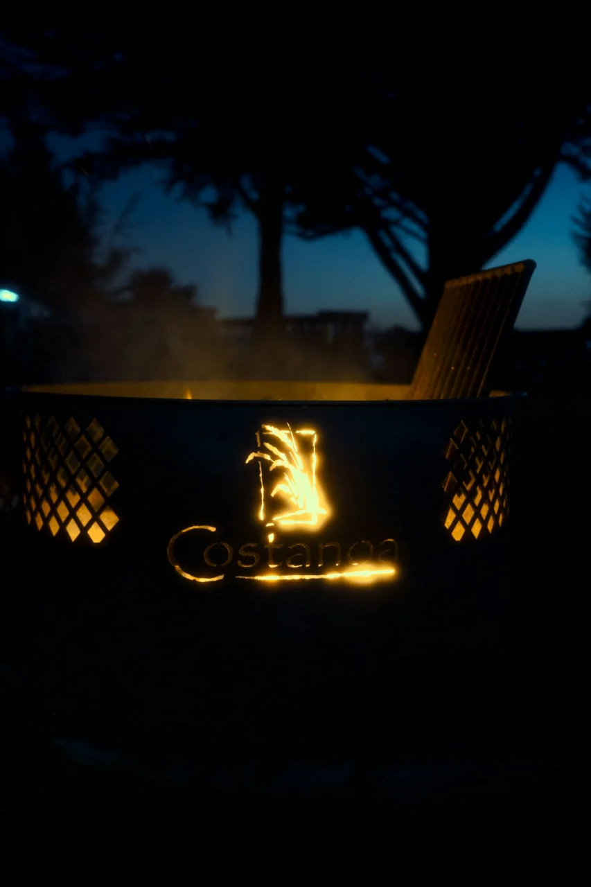 Glowing fire pit with logo at dusk