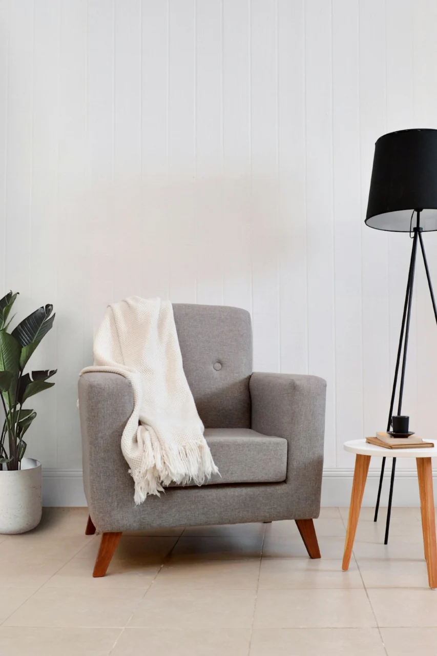Gray armchair with throw blanket and floor lamp