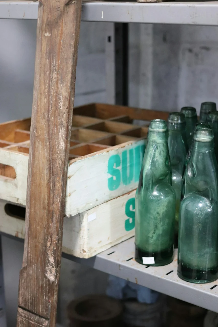 Green glass bottles on a shelf with crates