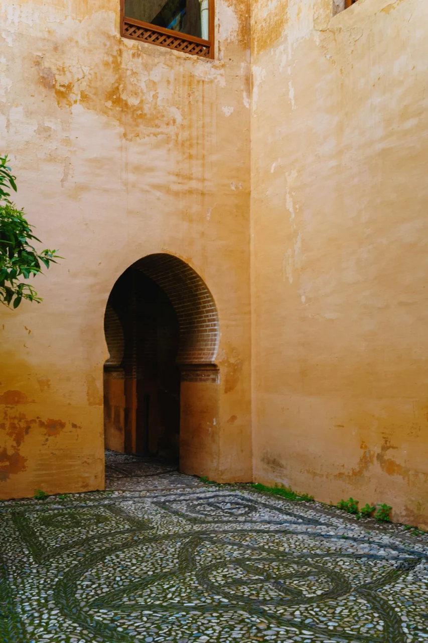 Historic courtyard with an arched entrance and mosaic pebble floor