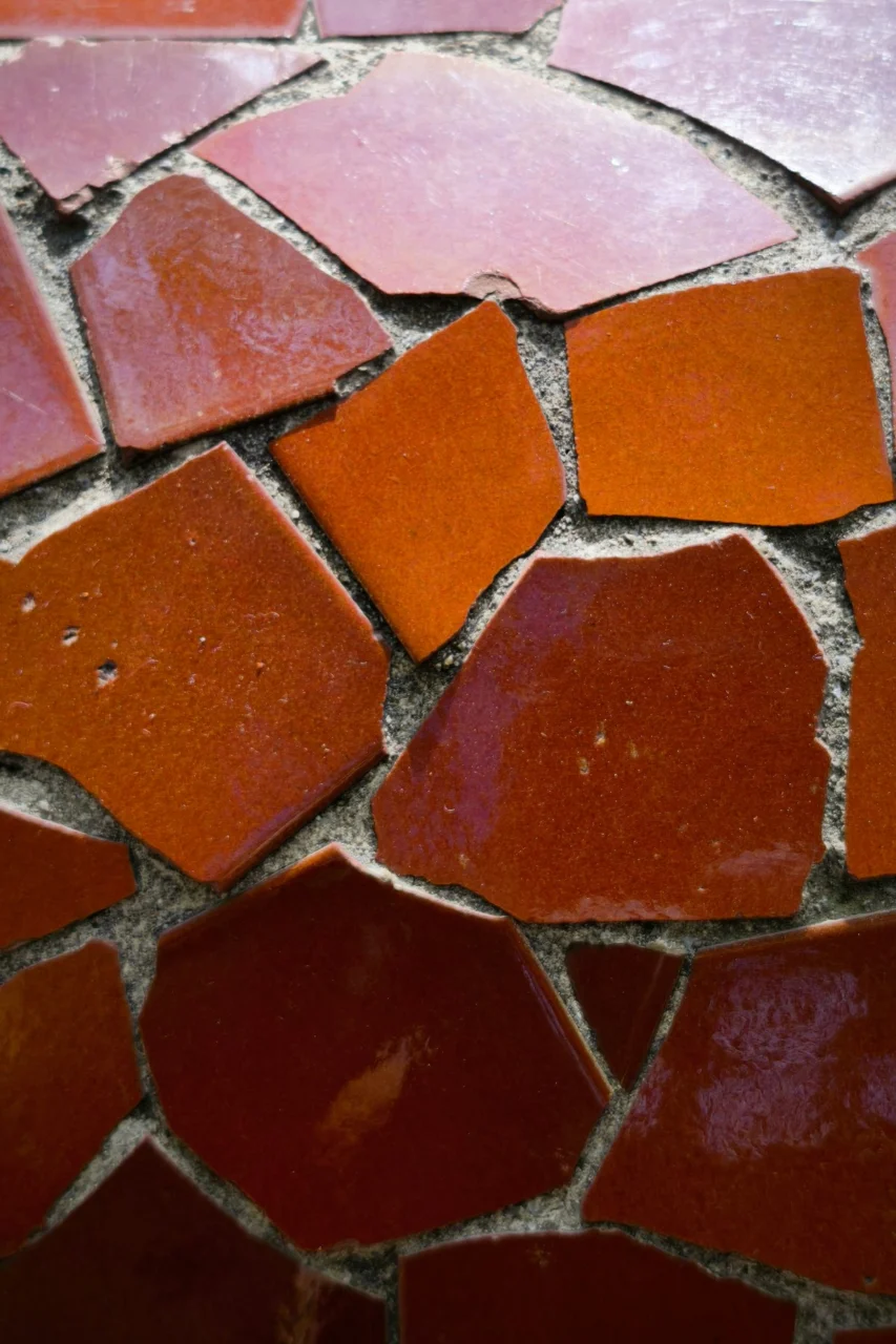 Irregular glossy orange ceramic tiles set in grey mortar
