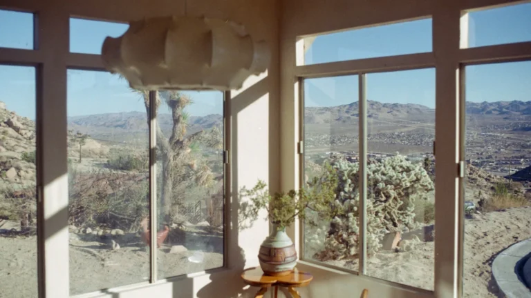 Large windows offer panoramic views of a sunny desert landscape