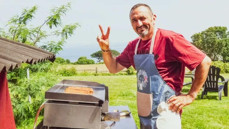Man grilling hot dogs and giving peace sign