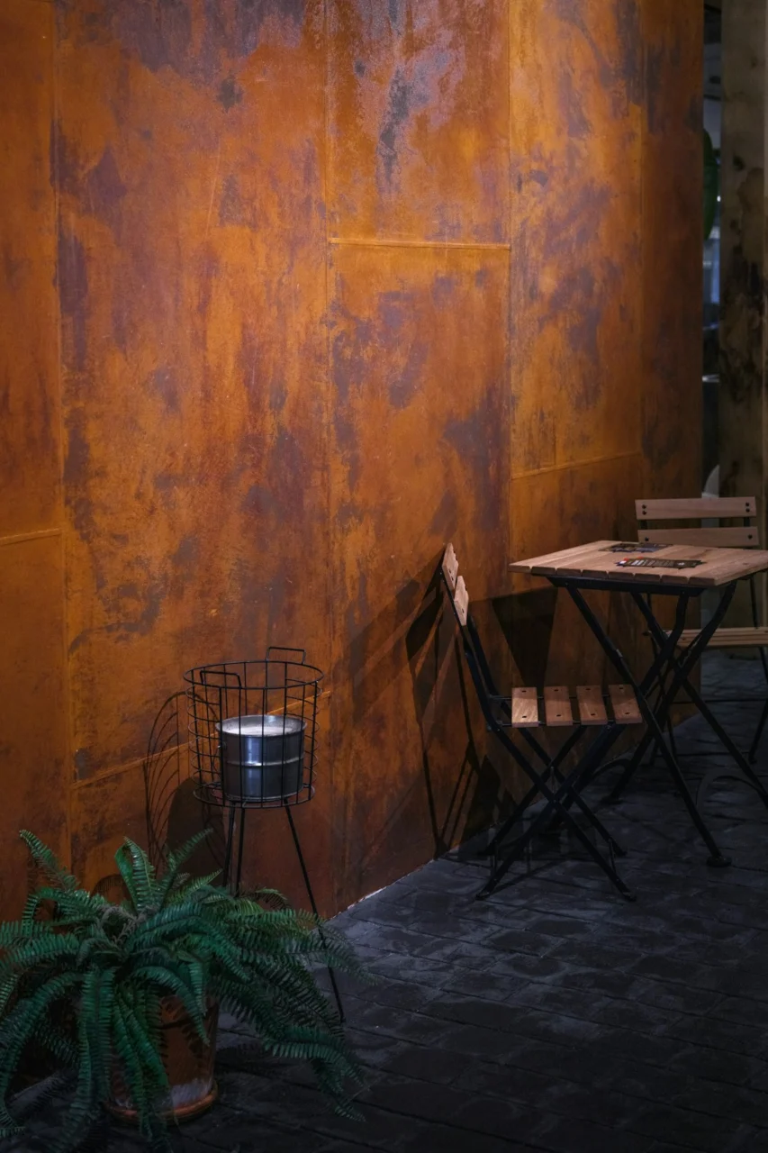 Metal wall with table and chairs in a plant