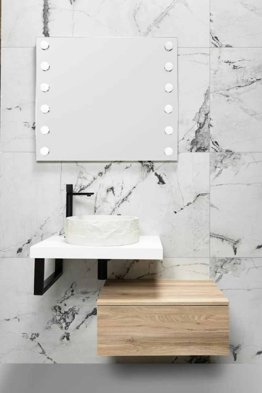 Modern bathroom with marble tiles, illuminated mirror, and wooden cabinet