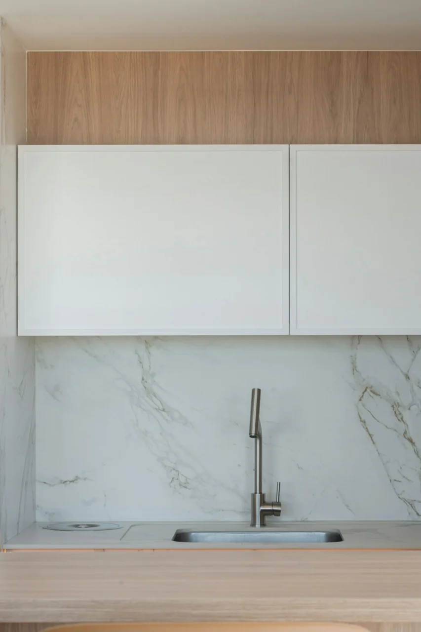 Modern kitchen with white cabinets, marble backsplash, and a sink