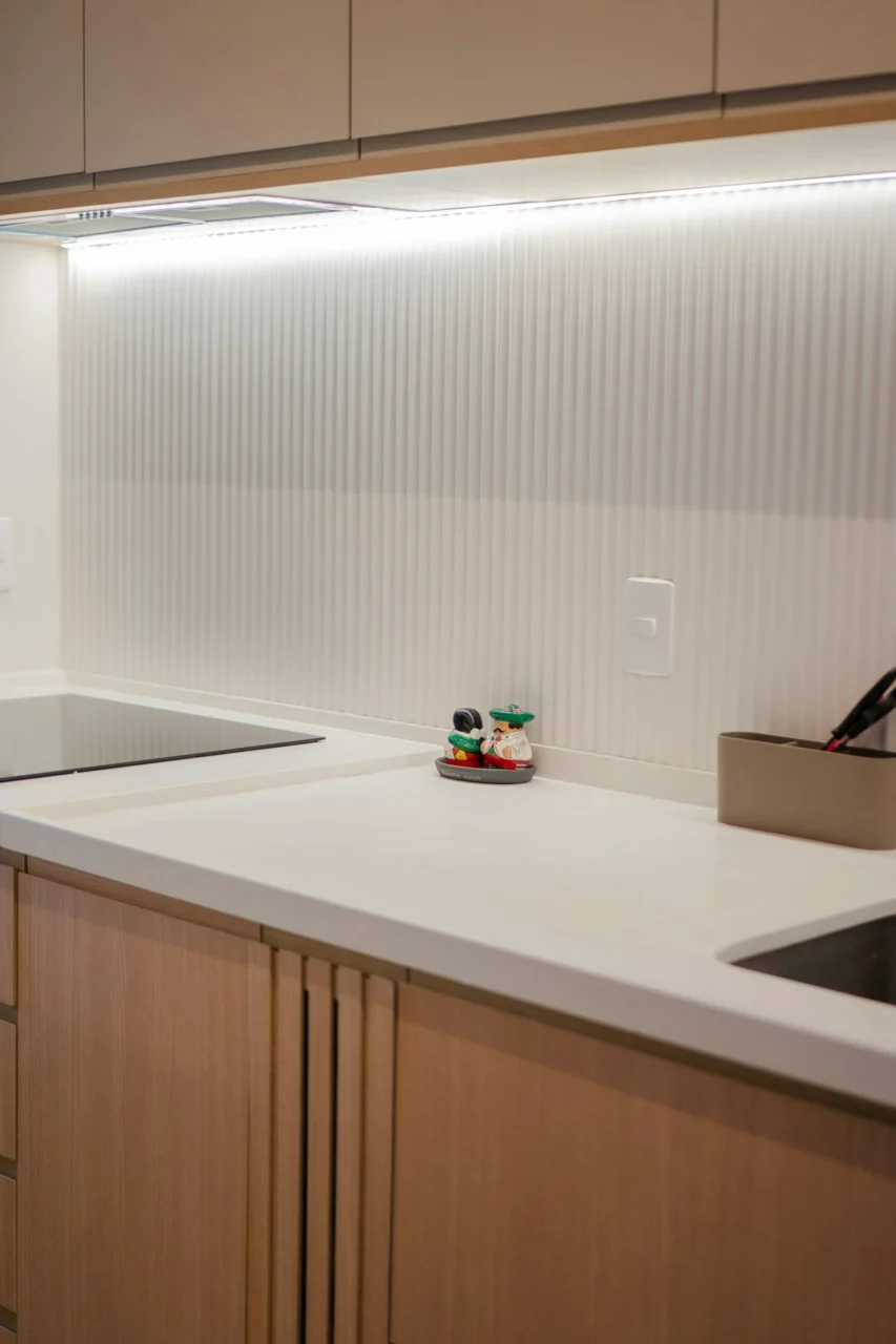 Modern kitchen with white counter, light wood cabinets, and cooktop