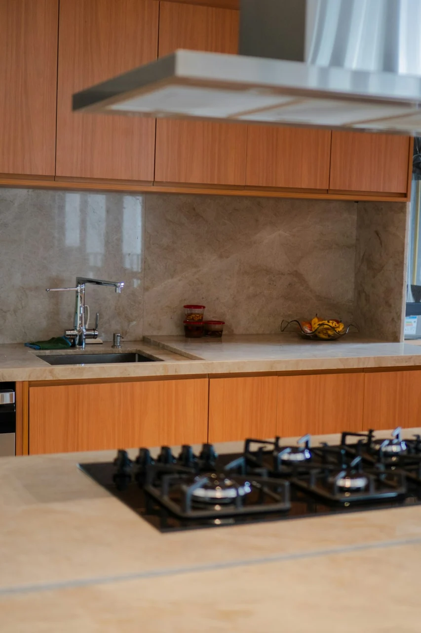 Modern kitchen with wooden cabinets, marble backsplash, and gas stovetop
