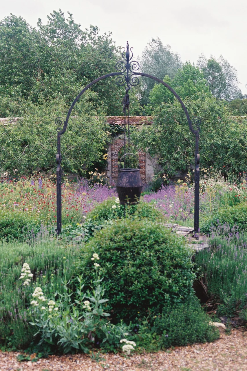 Ornate iron well in a vibrant, green garden