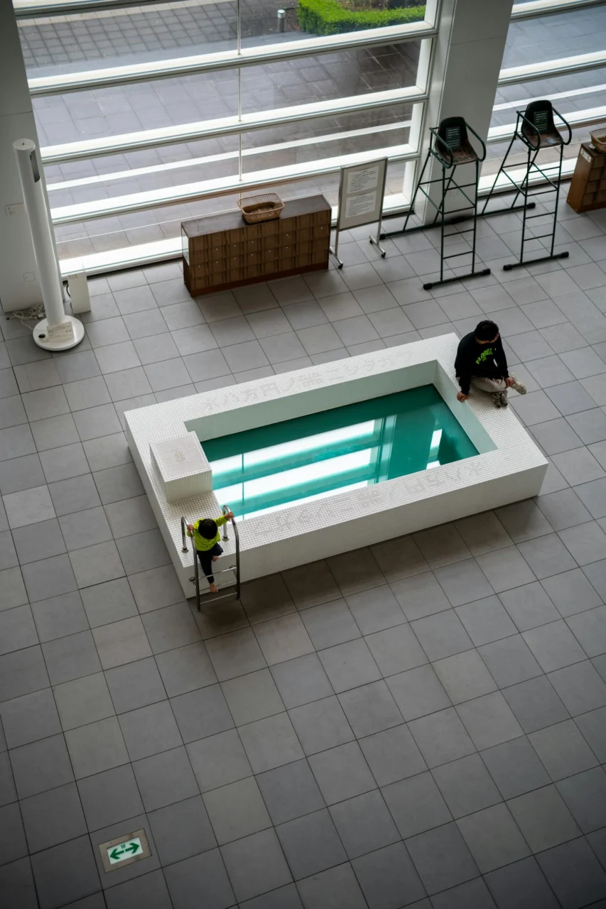 People at a building with a rectangular pool
