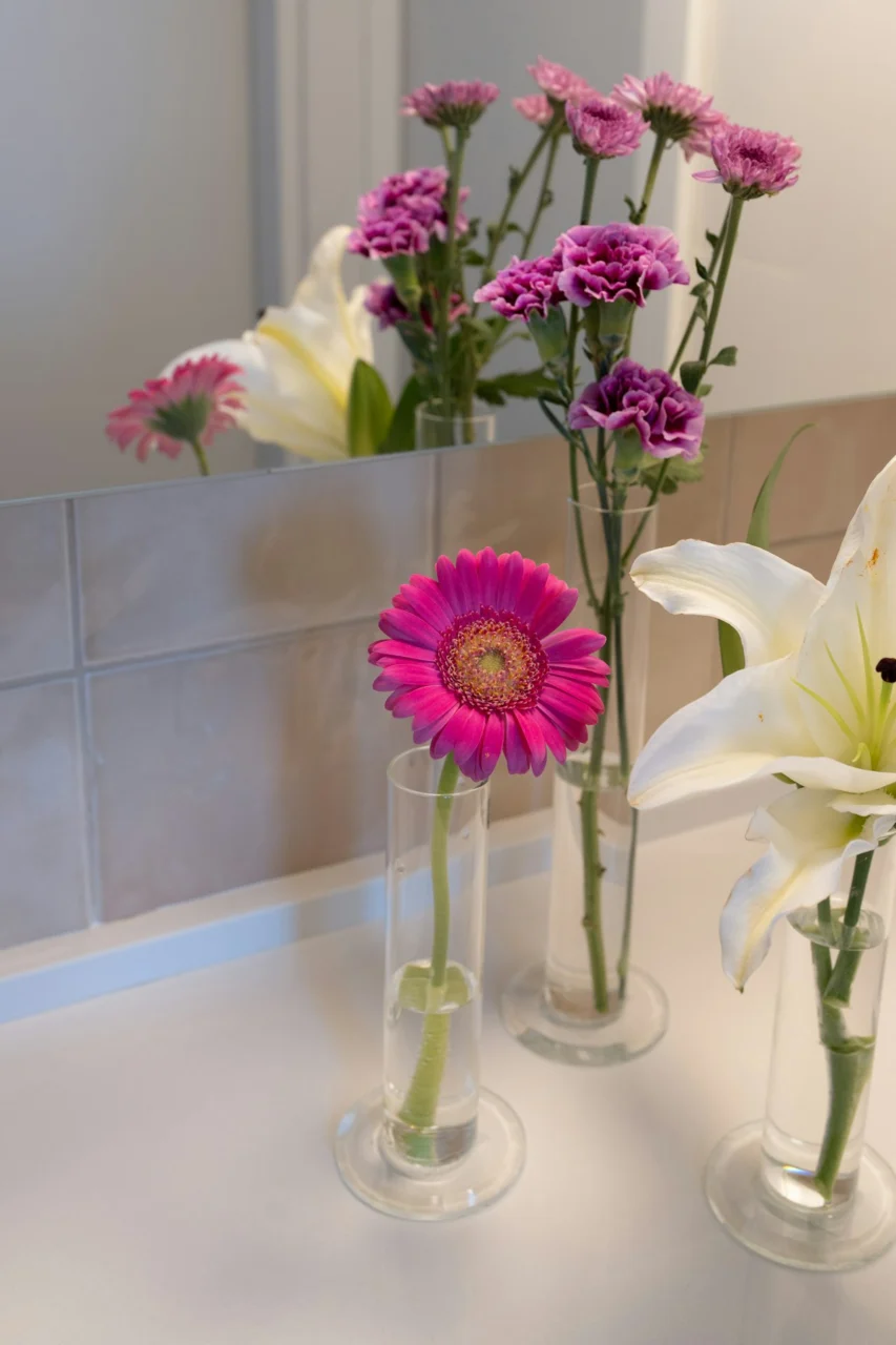 Pink gerbera, purple chrysanthemums, and white lilies in vases