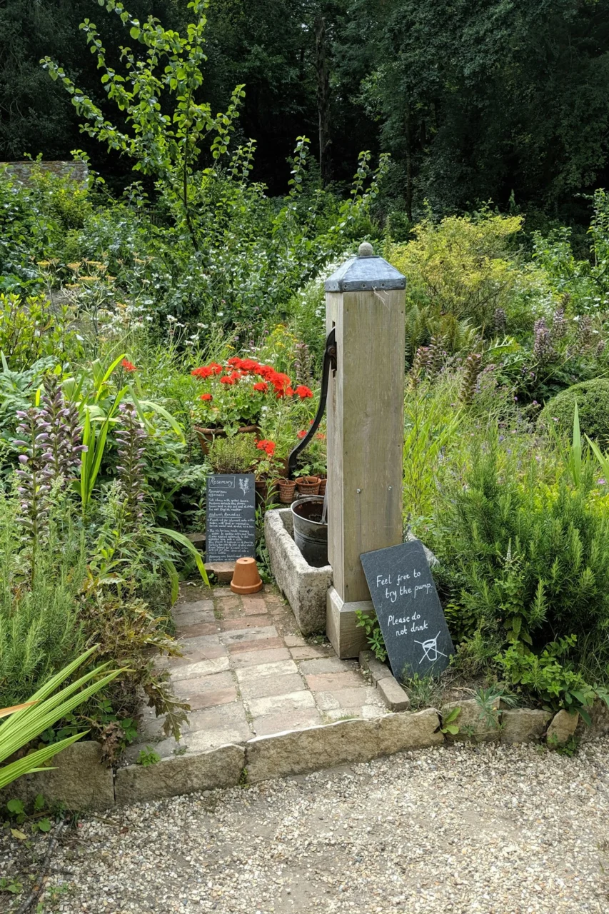 Stone water pump in a lush garden with signs